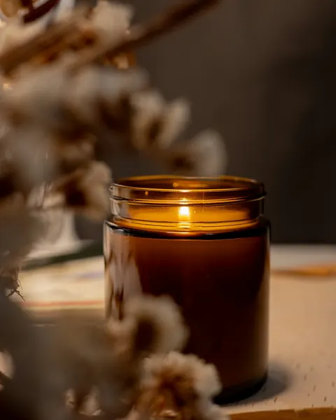 Lit candle in an amber glass jar